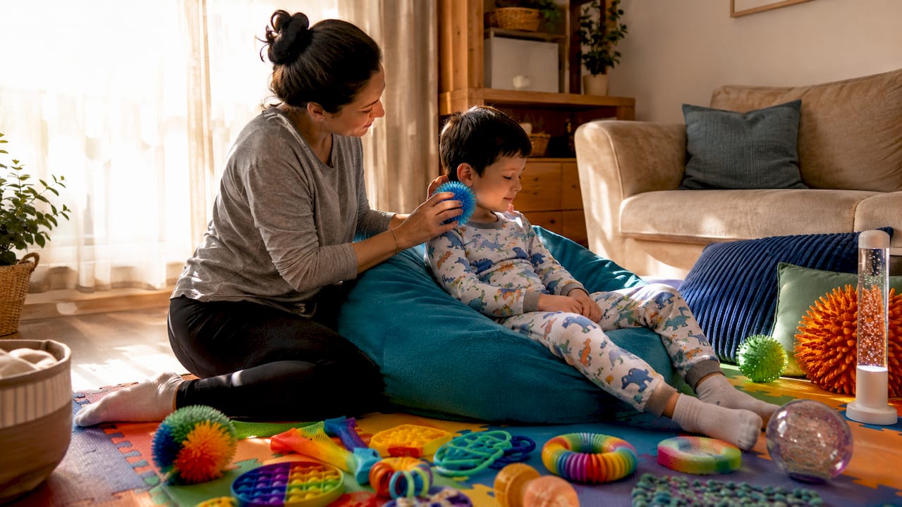 Caregiver hands holding sensory brush near child