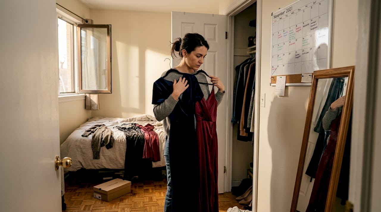 Woman comparing two evening dresses at home