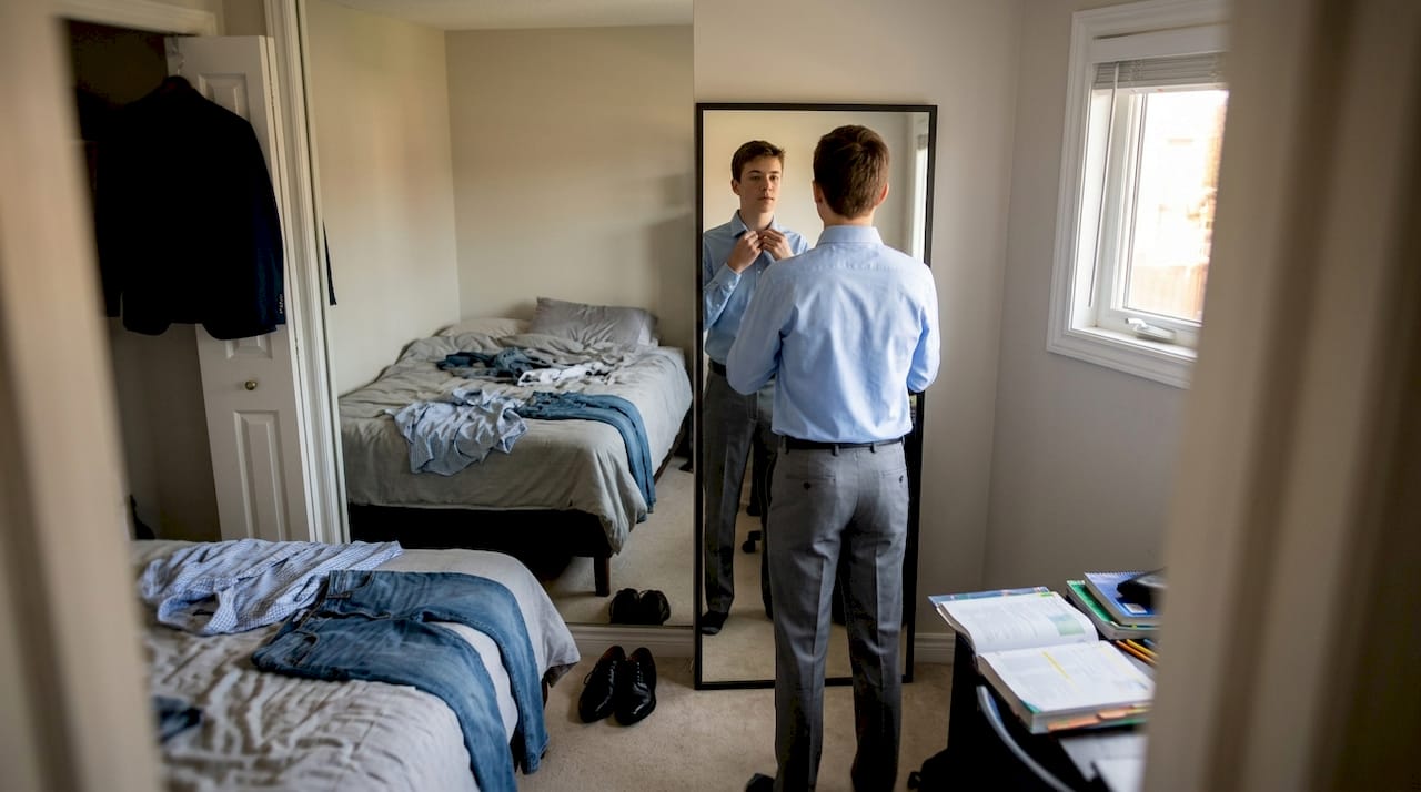 Teen boy selects outfit in bedroom before speech