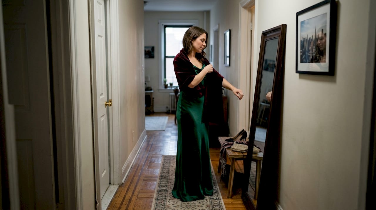 Woman layering formalwear in hallway mirror