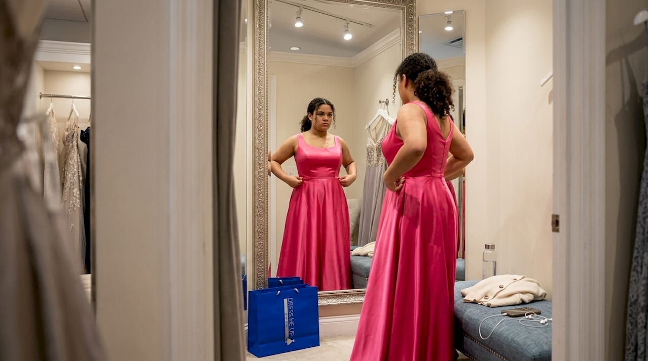 Teen fitting hot pink prom dress in boutique