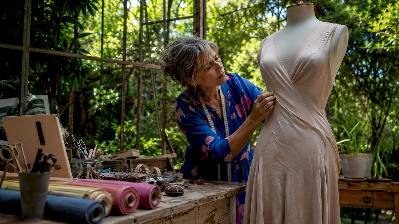 Dressmaker adjusting 1930s bias-cut gown on mannequin