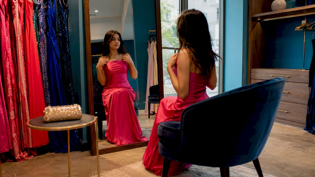 Teen woman trying affordable prom dress in boutique