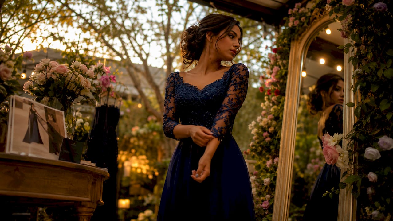 Woman adjusting blue 3/4 sleeve formal gown in boutique