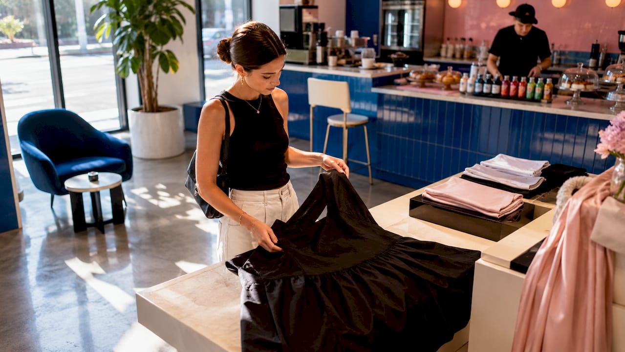 Woman examining drop-waist formal dress in boutique