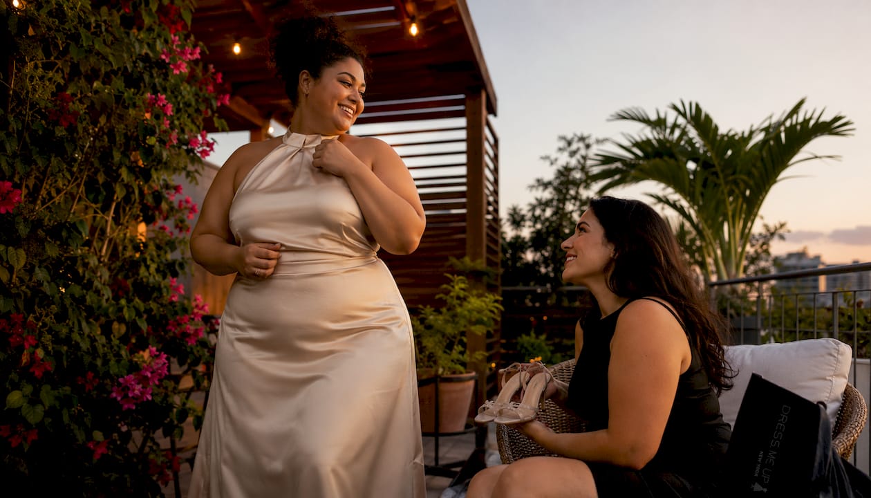 Woman trying on halter bridesmaid dress with friend