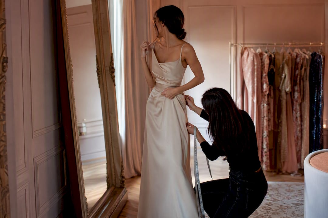 Petite woman adjusting gown fit in mirror