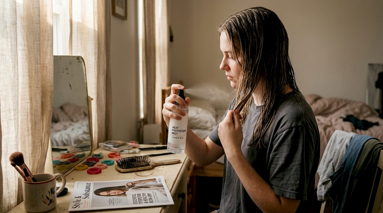 Applying heat protectant spray to hair