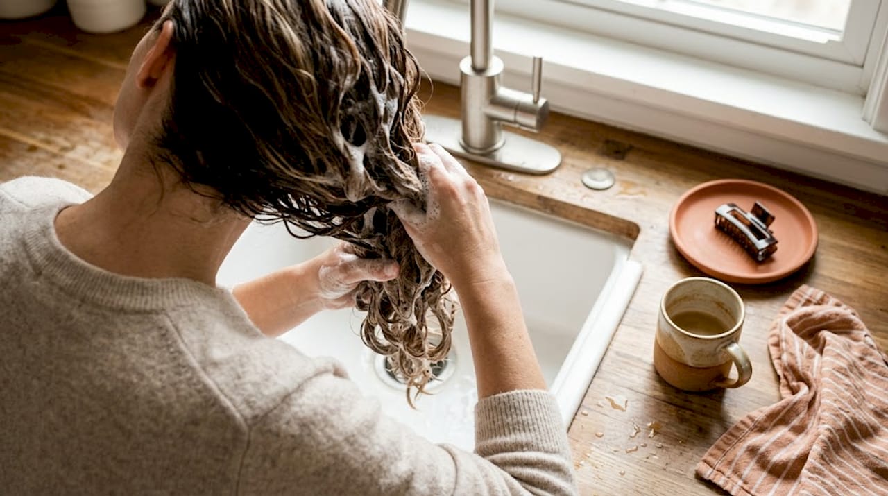 Hands lathering sulfate-free shampoo in hair