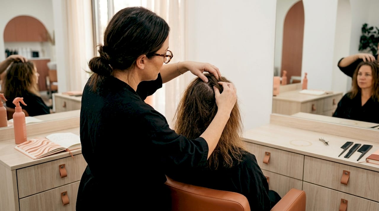 Hairdresser examining client’s scalp for dryness