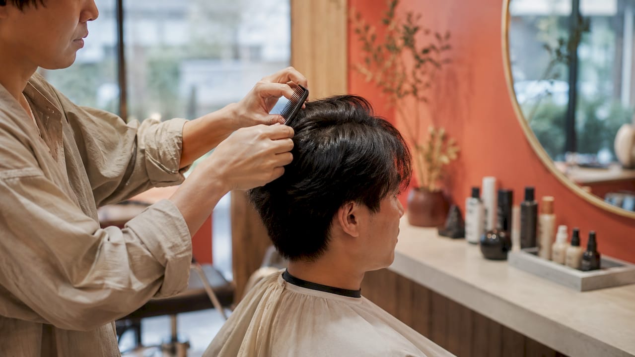 Stylist sectioning man's hair during consultation