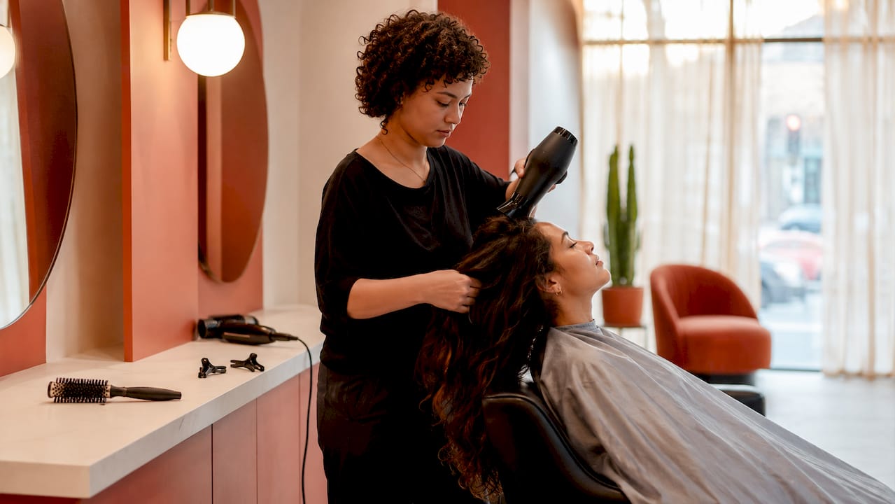 Hairstylist blow-drying hair in salon