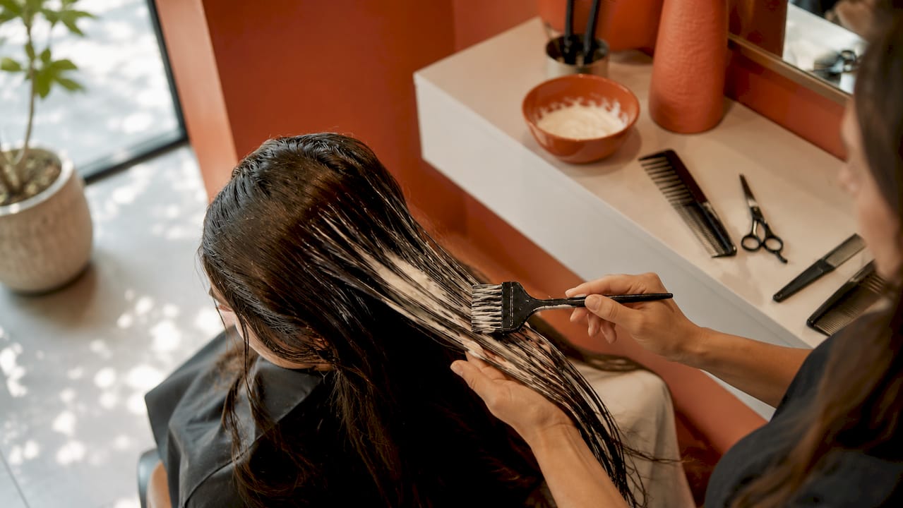 Stylist applying conditioner to hair mid-lengths