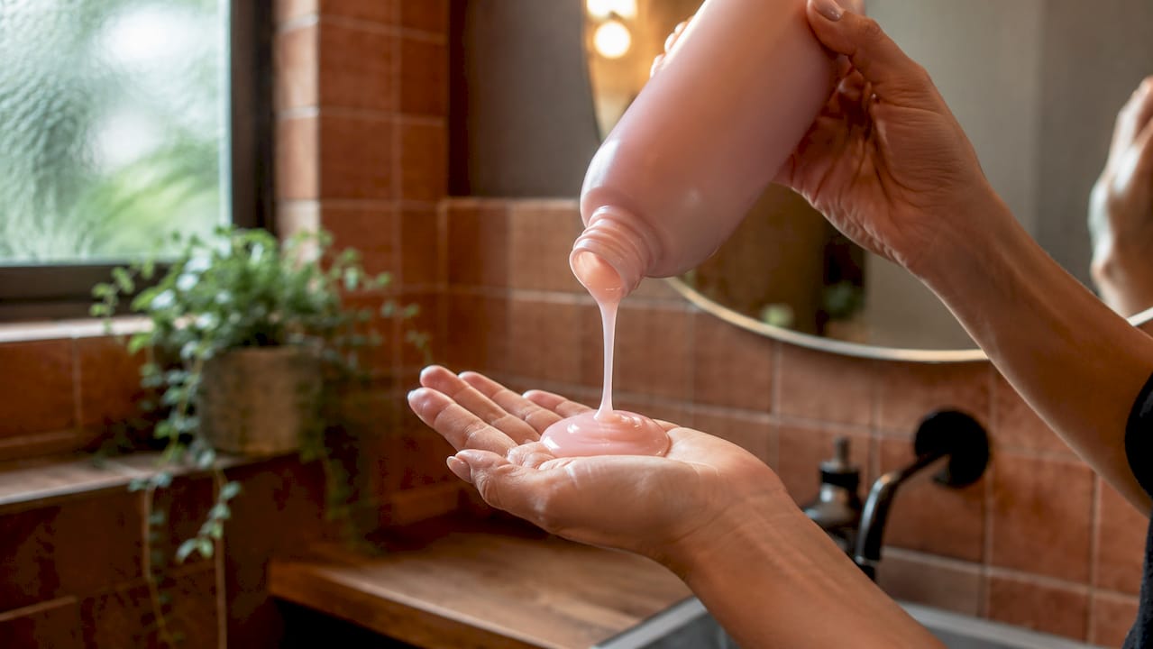 Hands applying pH-balanced shampoo in shower