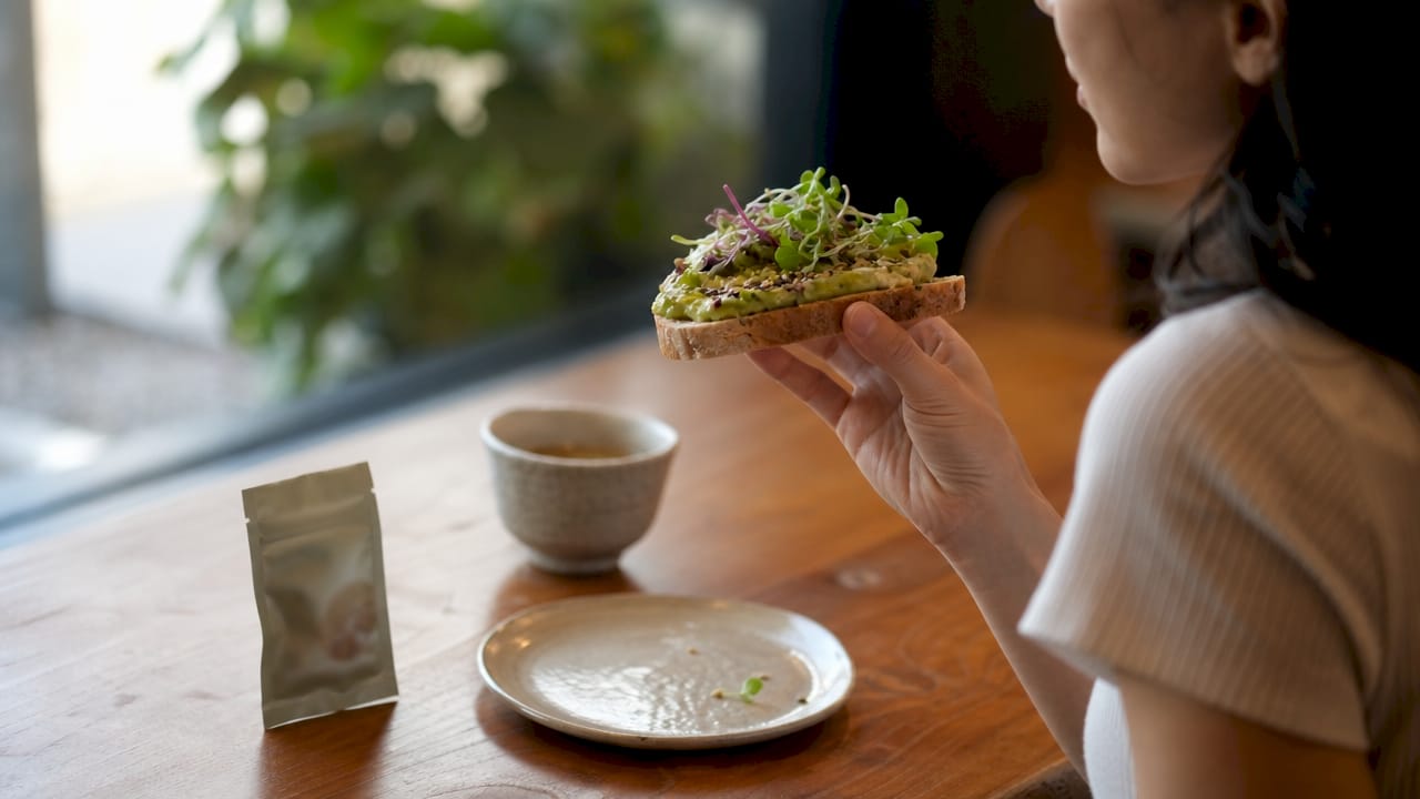 Hand holding avocado toast near cannabis edibles