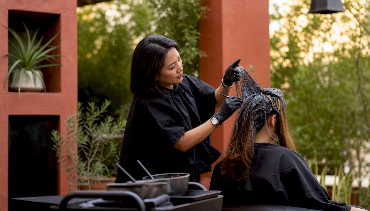 Hair colorist applying corrective hair color in salon