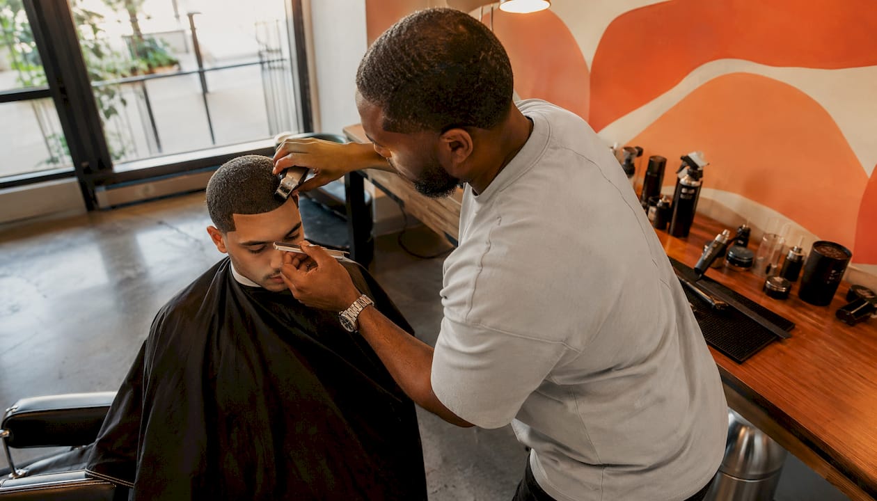 Barber creating sharp hairline in vintage barbershop