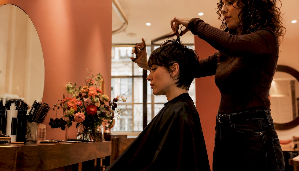Hairdresser trimming trendy bixie haircut in salon