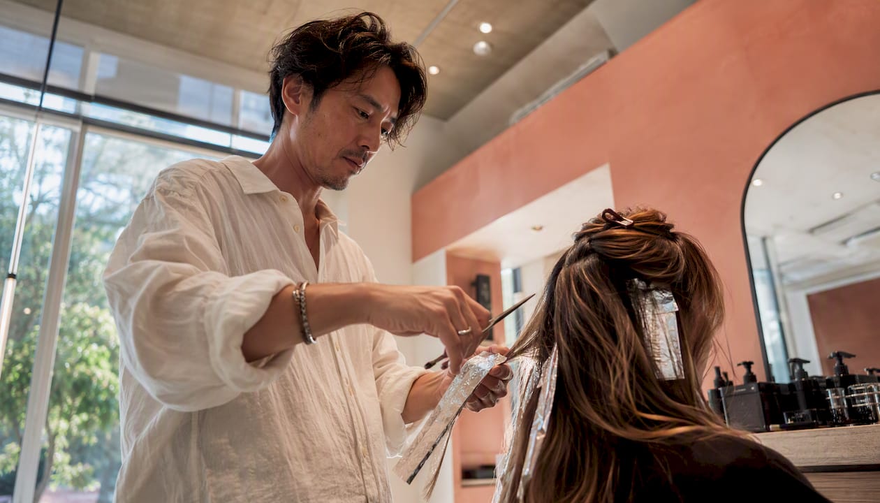 Hairstylist applying highlights before haircut