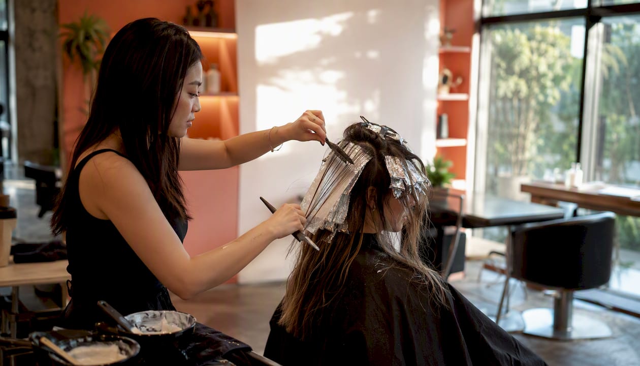 Stylist hands applying varied hair color techniques