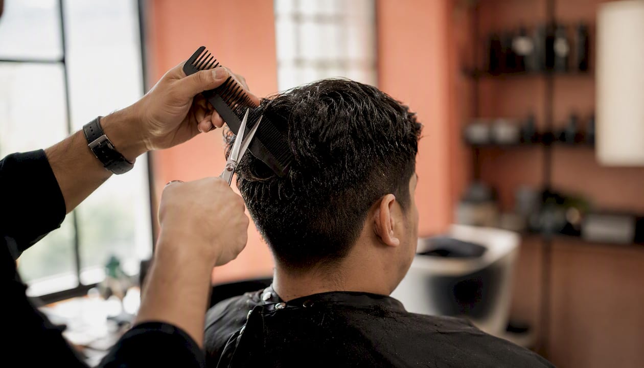 Close-up of barber's hands trimming hair with scissors