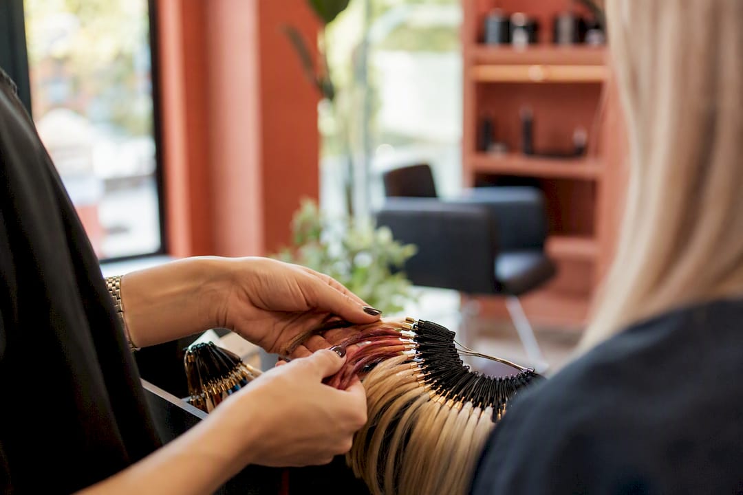 Hands comparing hair color swatches in salon