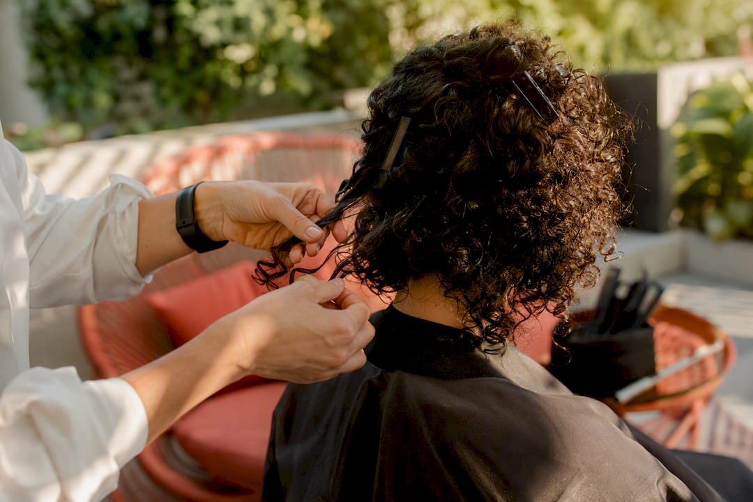 Stylist hands sectioning curly hair during consultation