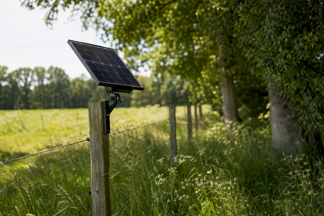 Solar panel mounted on fence post with tree shadows