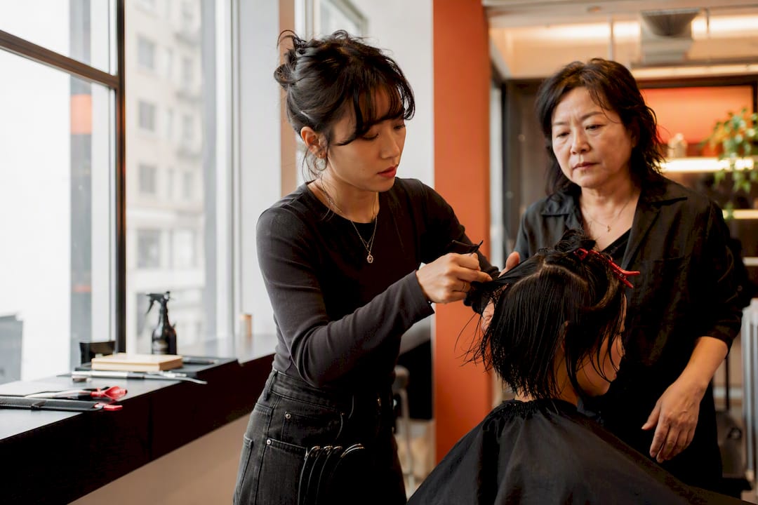 Beauty school student cutting hair under supervision