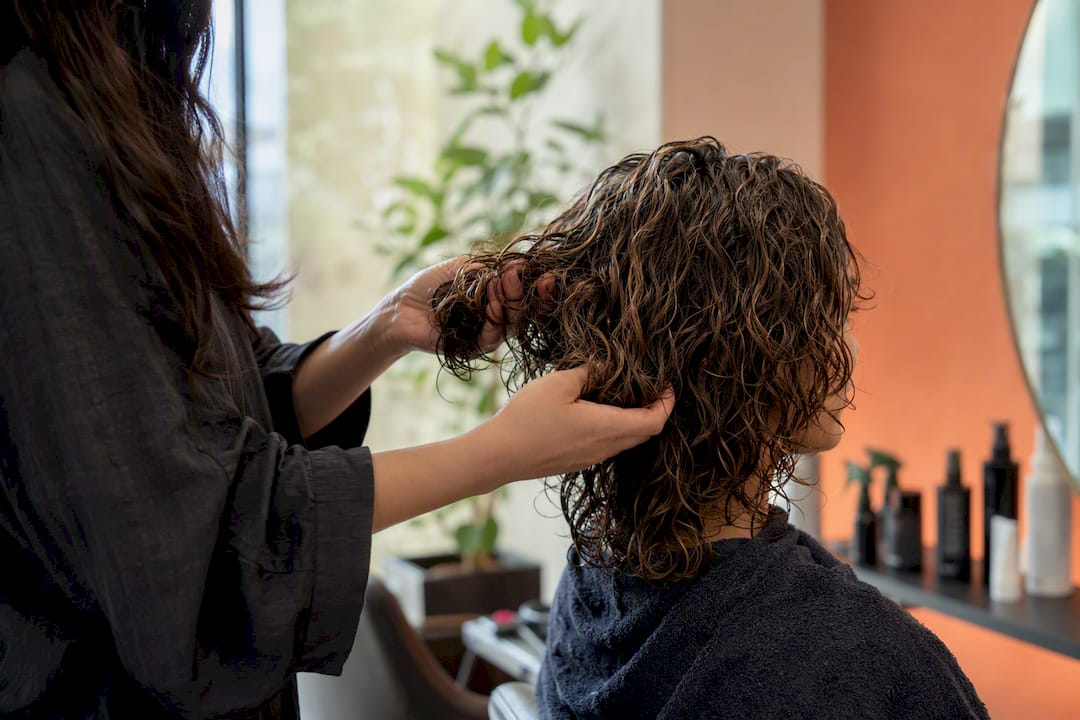 Hands scrunching curly hair to finish style