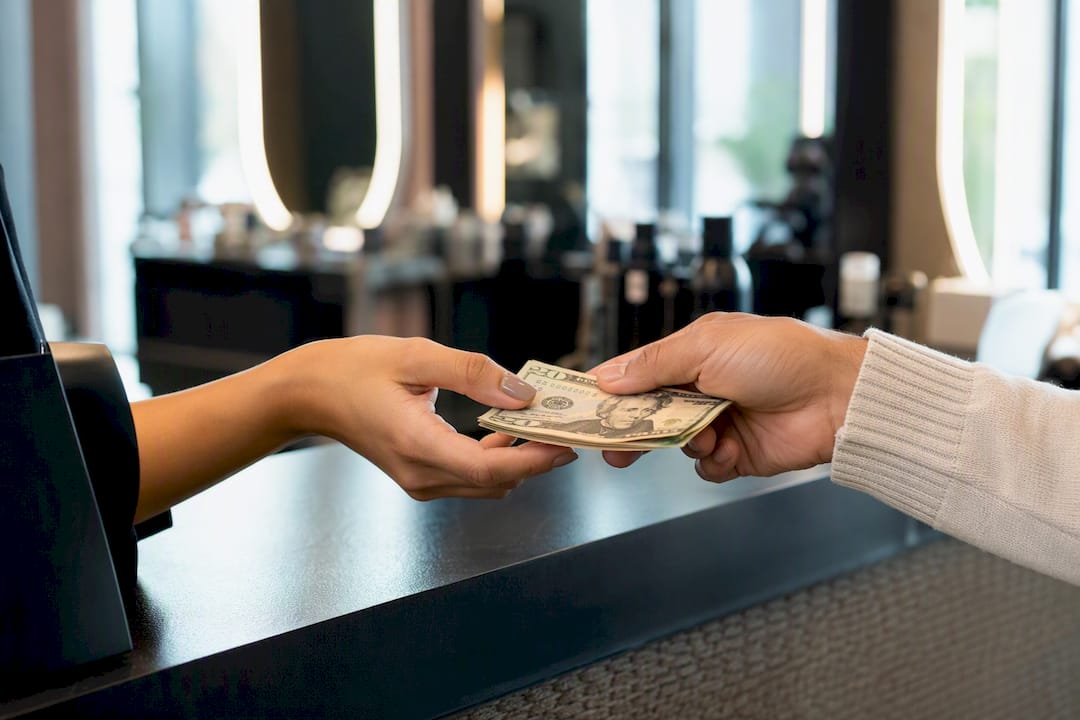Client handing cash tip to stylist