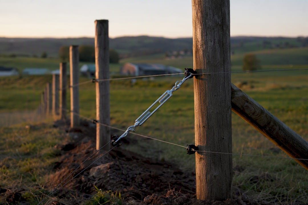 Partly finished farm fence with tensioned wires