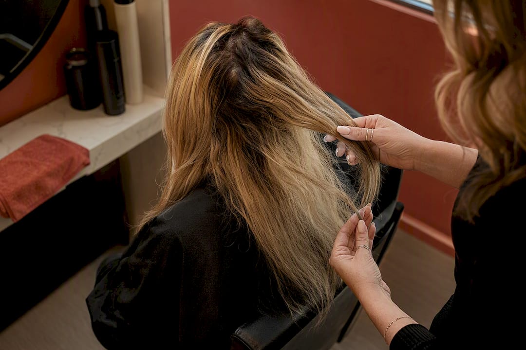 Colorist assessing uneven hair color in salon