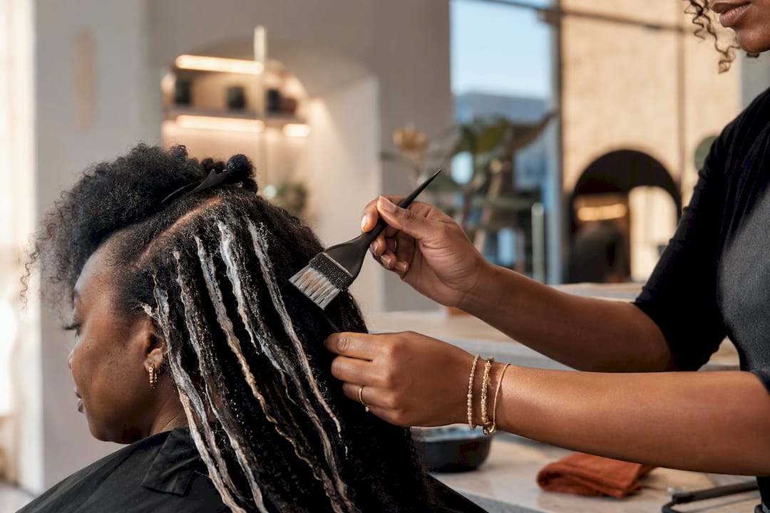 Colorist hand painting balayage on textured hair