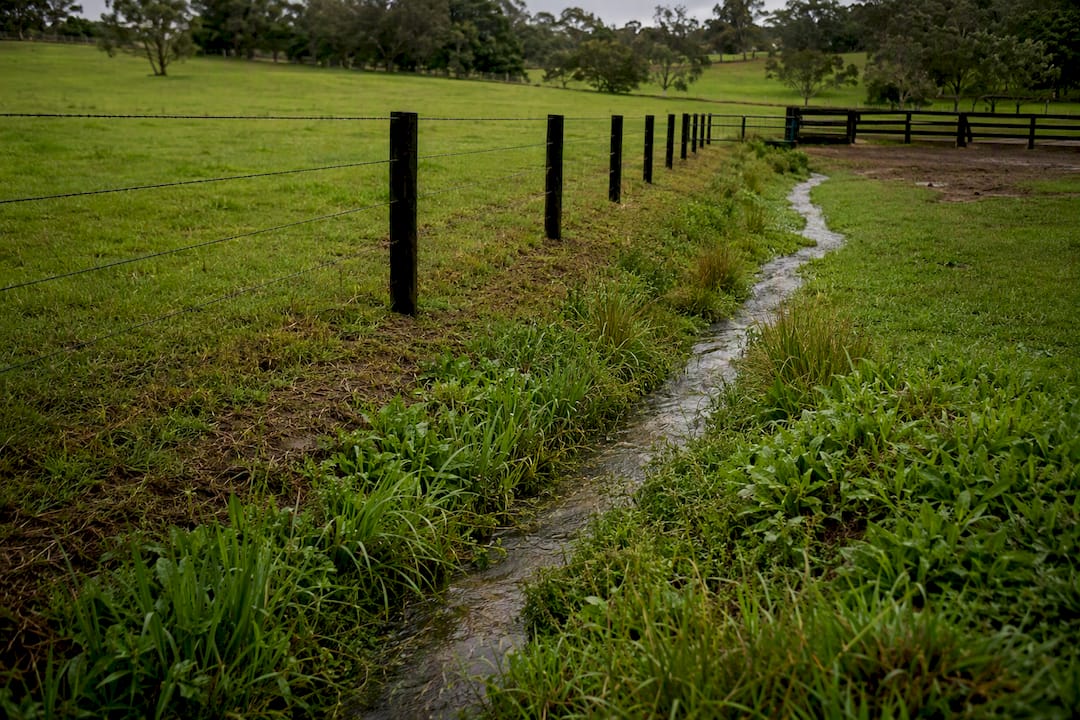 Contour fence guiding runoff across pasture