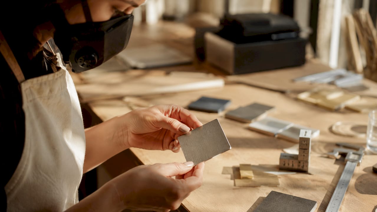 Im Labor wird ein Stück eloxiertes Aluminium sorgfältig in den Händen gehalten.