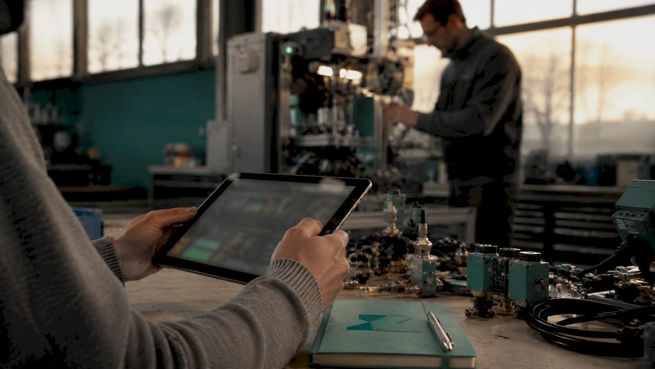 Hands holding tablet near manufacturing machine