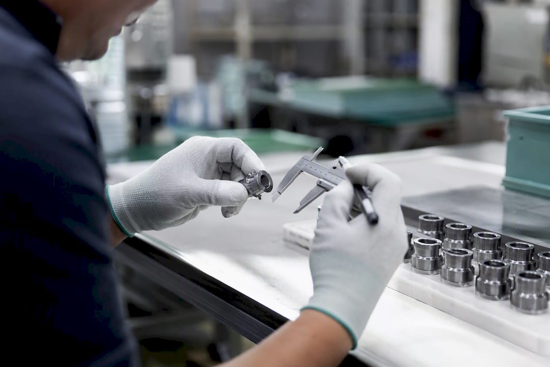 Inspector measuring machined part manually