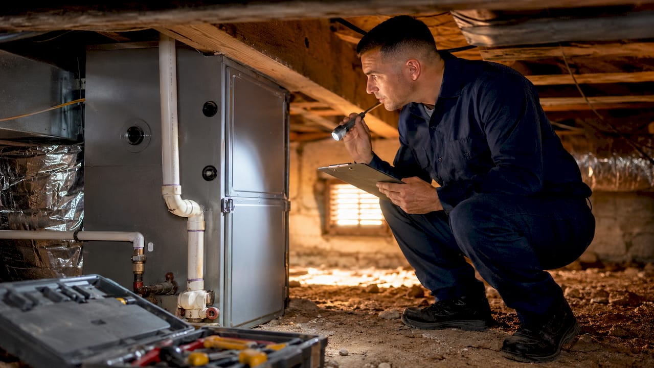 HVAC technician inspecting furnace with clipboard