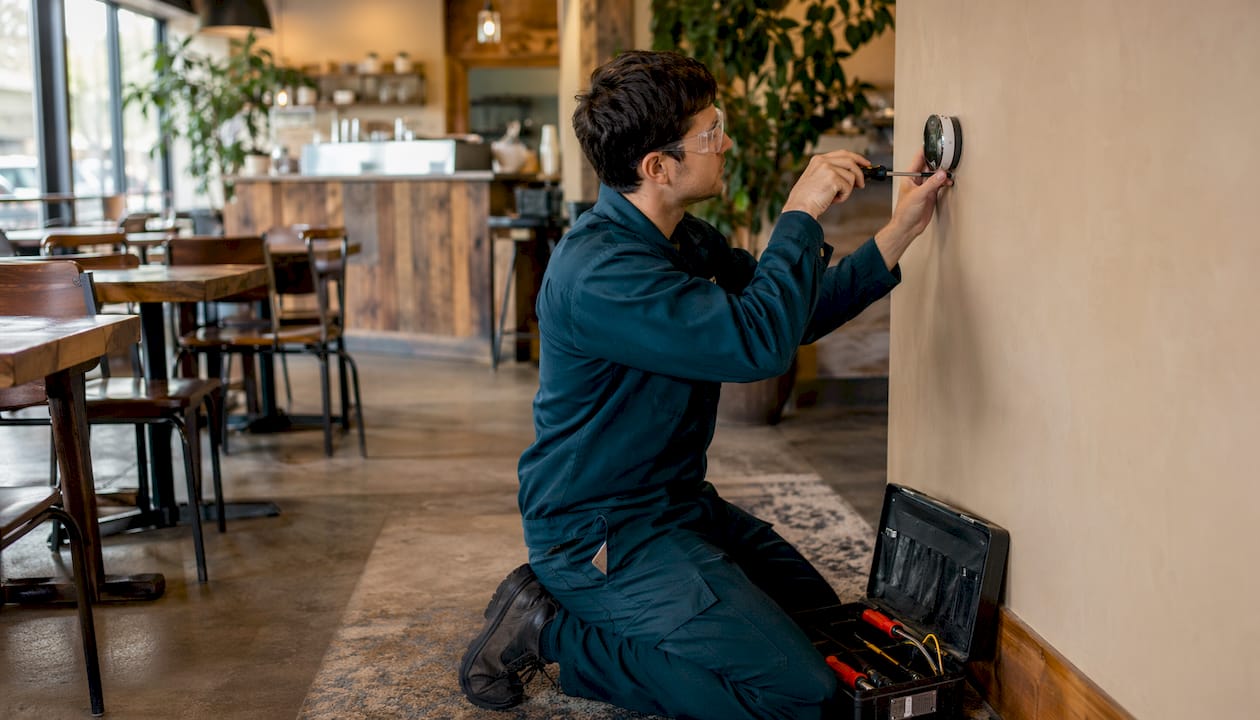 Technician installing smart thermostat indoors