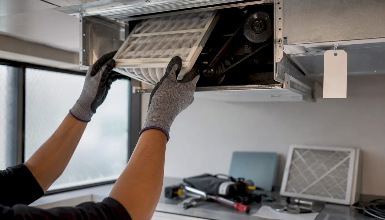 Hands replacing office ventilation filter