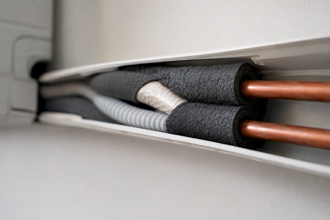 Close-up inside aircon pipe trunking showing pipes and insulation