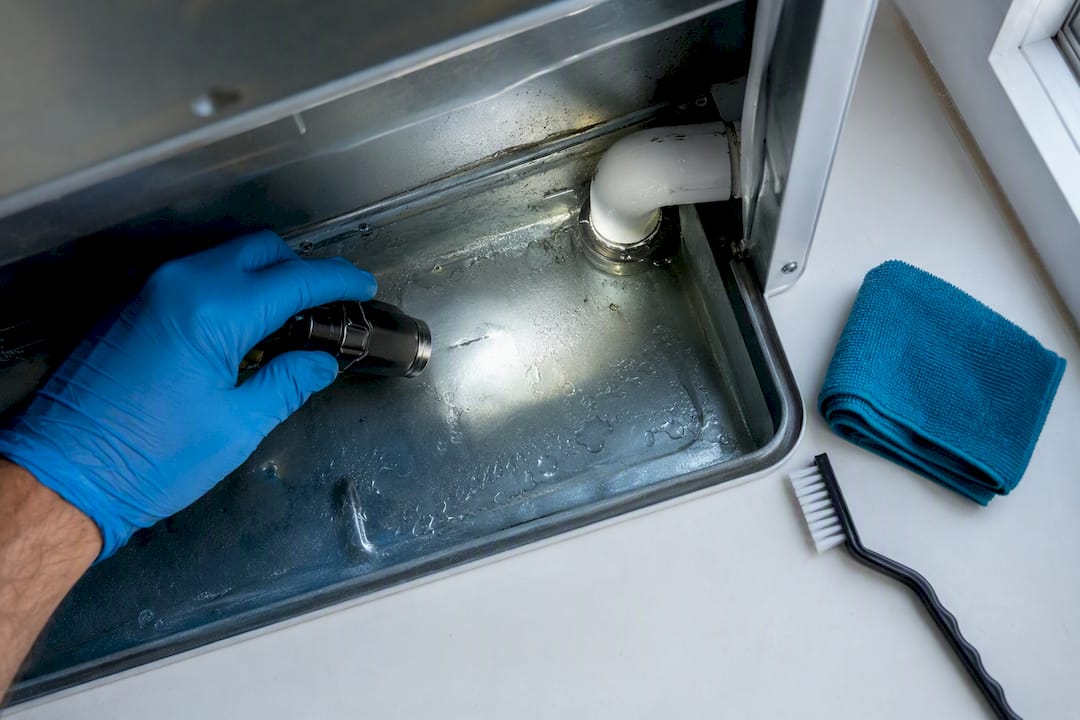 Technician inspecting water in condensate drain pan