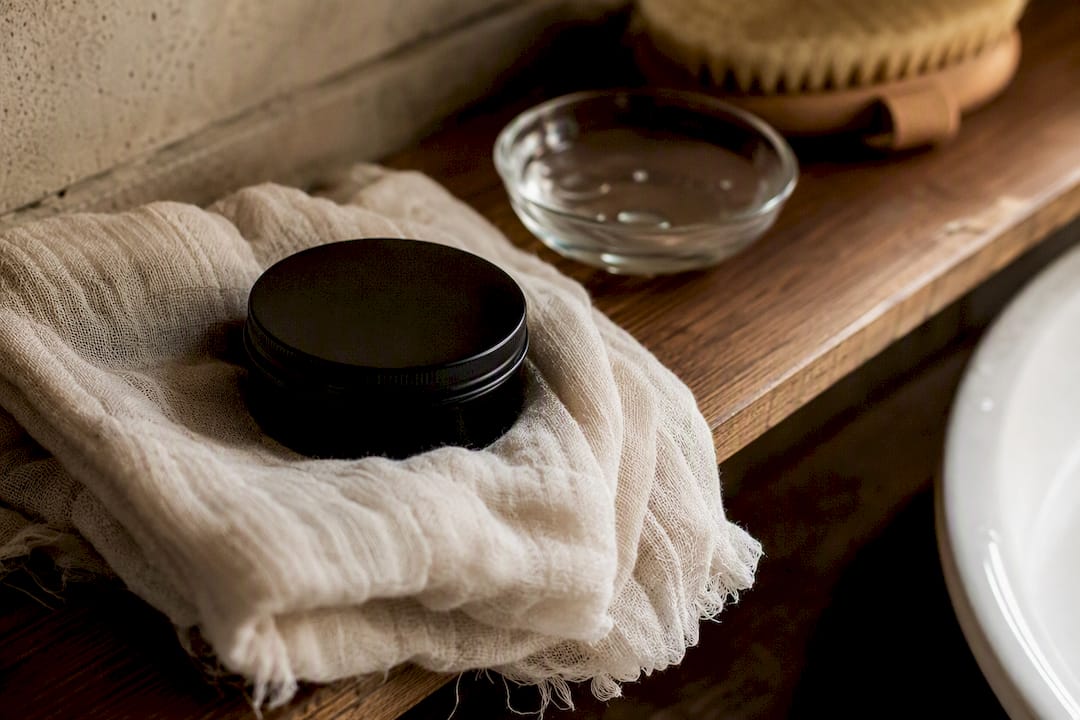 Soft muslin cloth and tallow balm lid on bathroom counter