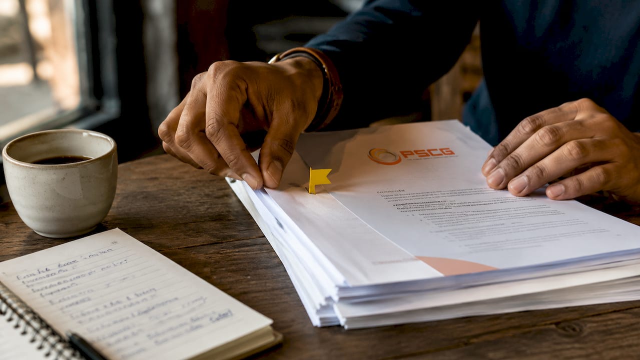 Hands arranging policy documents with red flag clip