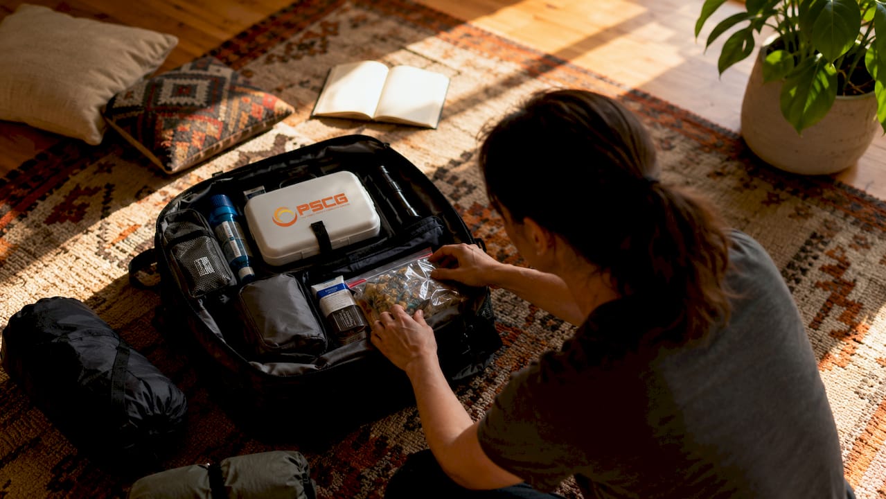 Hands assembling emergency supply kit with PSCG first aid kit