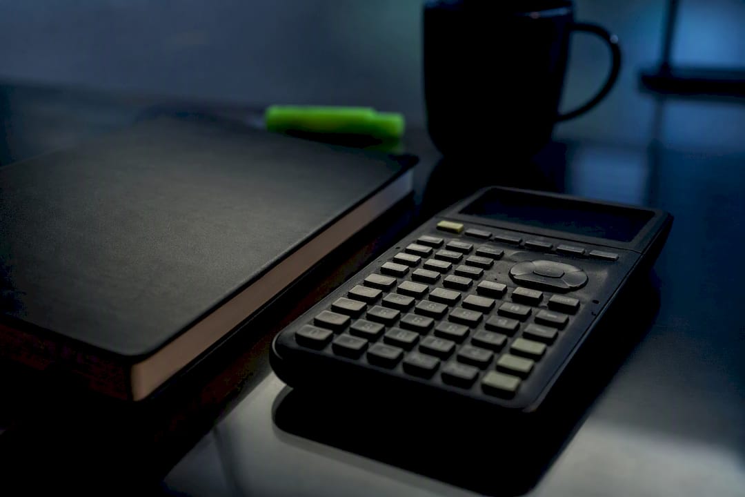 Calculator and notebook on black desk
