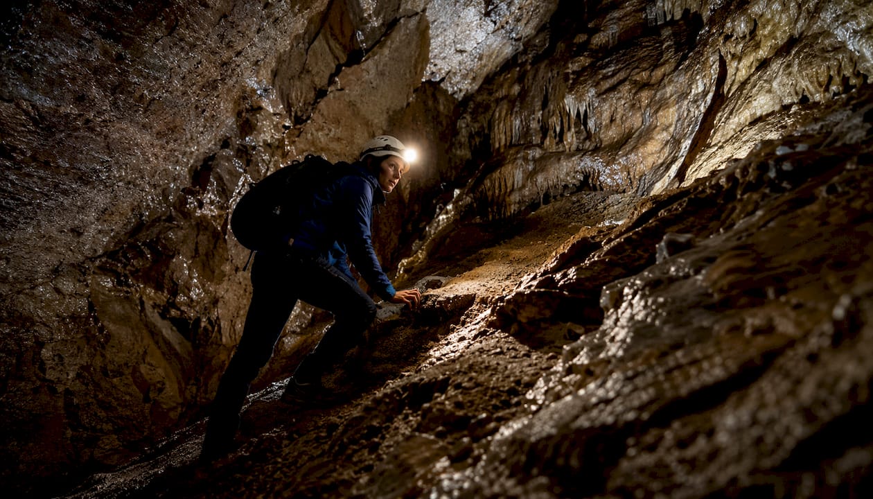 Adventurer exploring narrow cave passage