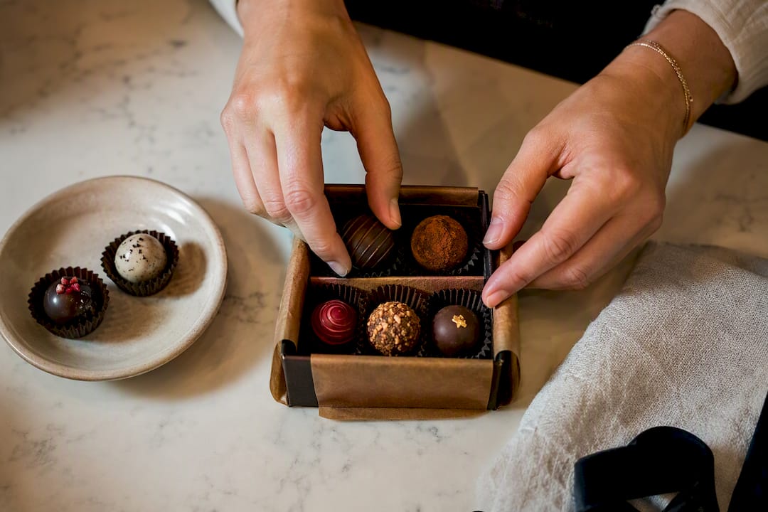 Hands arranging artisan truffles in a gift box