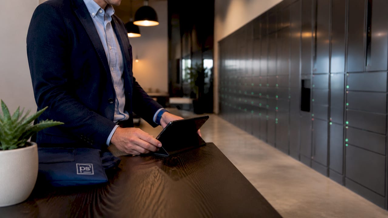 Hands using tablet beside electronic package lockers